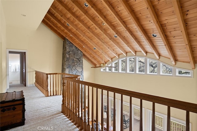 hall featuring high vaulted ceiling, wooden ceiling, light carpet, and beamed ceiling