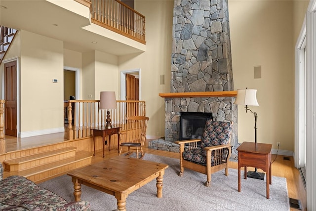 interior space with a high ceiling, light wood-type flooring, and a stone fireplace