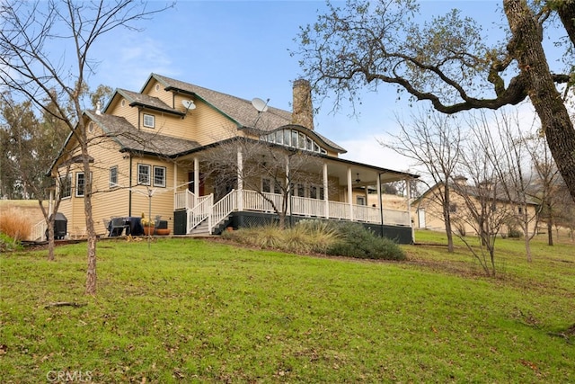 rear view of property with covered porch and a lawn