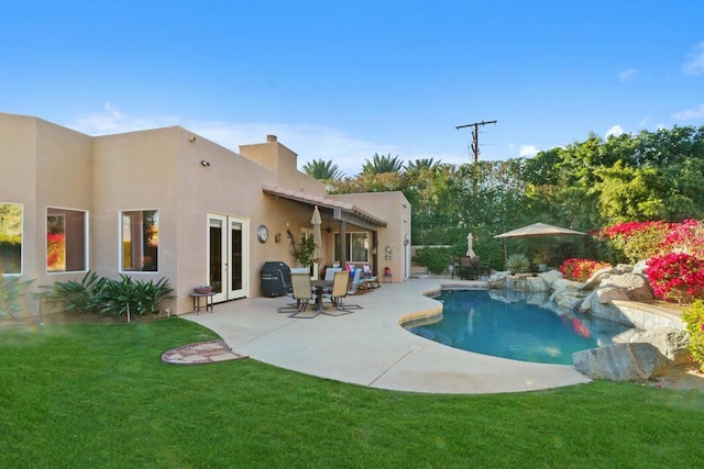 view of swimming pool featuring french doors, a lawn, and a patio