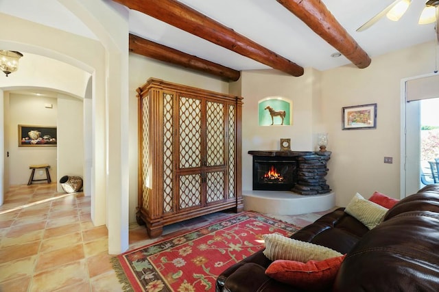 living room featuring ceiling fan, light tile patterned floors, and beamed ceiling