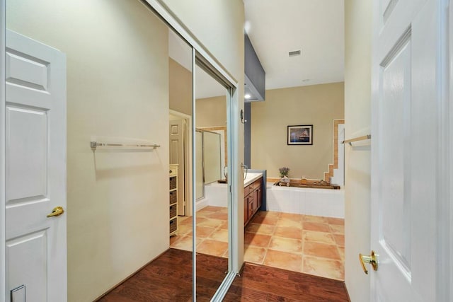 bathroom featuring hardwood / wood-style flooring, tiled tub, and vanity