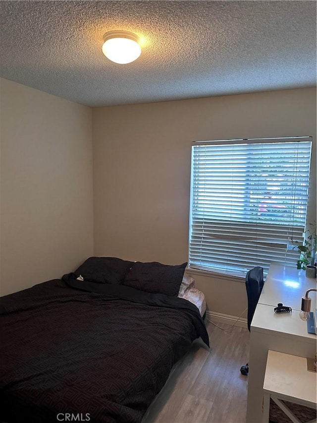 bedroom with multiple windows, a textured ceiling, and hardwood / wood-style floors