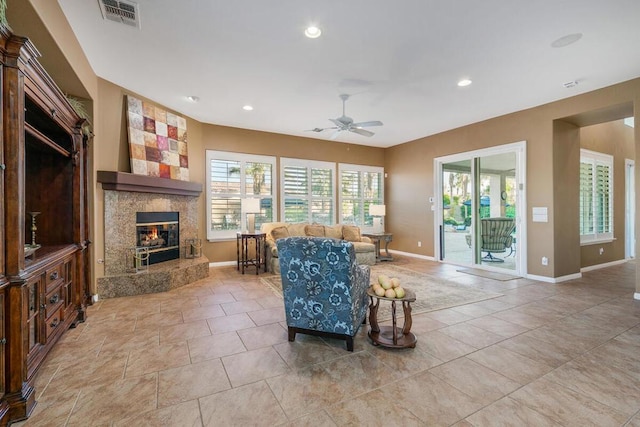 tiled living room featuring a fireplace and ceiling fan