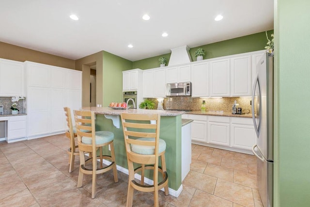 kitchen featuring stainless steel appliances, a kitchen bar, a center island with sink, and backsplash