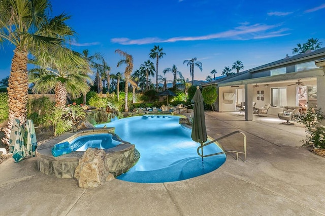 pool at dusk featuring outdoor lounge area, a patio, ceiling fan, and an in ground hot tub