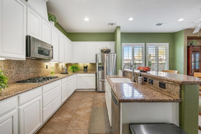 kitchen featuring appliances with stainless steel finishes, sink, a kitchen island with sink, and a breakfast bar area