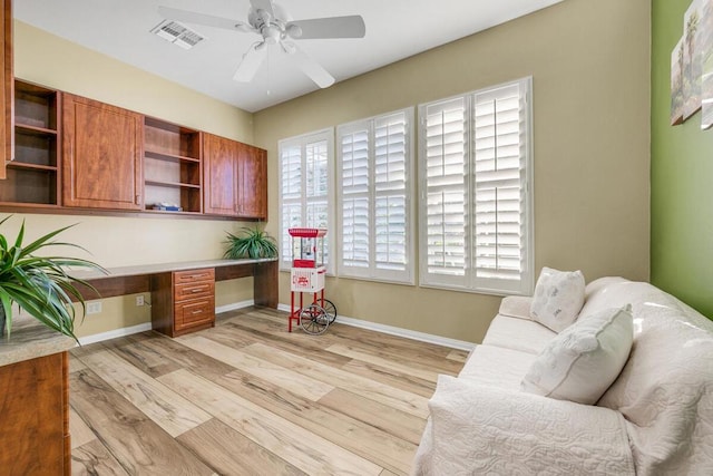 office area with built in desk, ceiling fan, and light wood-type flooring