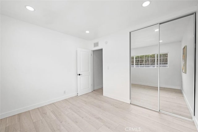 unfurnished bedroom featuring light hardwood / wood-style flooring and a closet