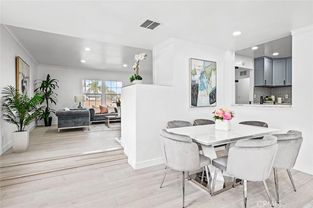 dining room with crown molding and light hardwood / wood-style flooring