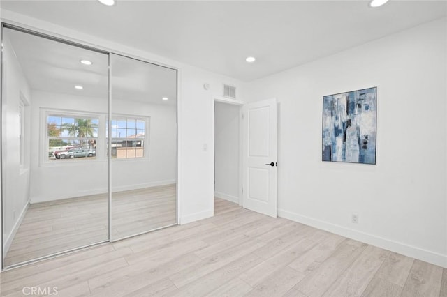 unfurnished bedroom with light hardwood / wood-style flooring and a closet