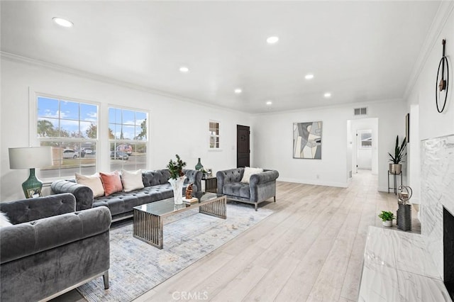 living room with crown molding, light wood-type flooring, and a fireplace