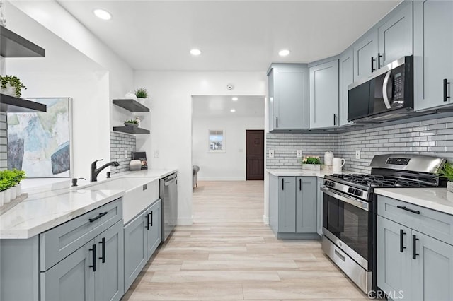 kitchen with backsplash, appliances with stainless steel finishes, and gray cabinetry