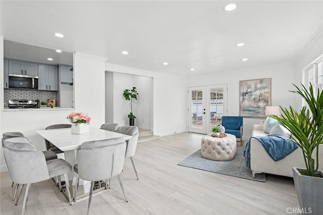 dining space featuring crown molding, light hardwood / wood-style floors, and french doors