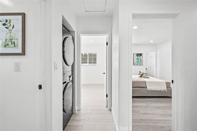 hallway with stacked washer / drying machine and light hardwood / wood-style flooring