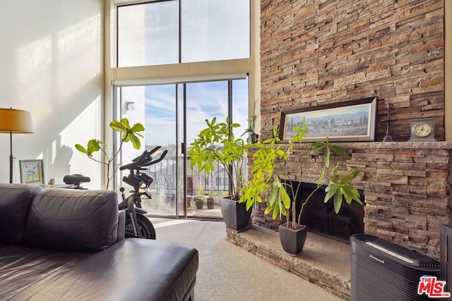 living room with carpet, a fireplace, and a towering ceiling