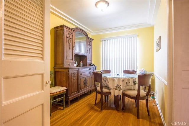 dining area featuring wood-type flooring and ornamental molding