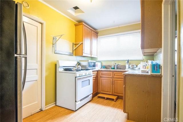 kitchen with light hardwood / wood-style floors, sink, appliances with stainless steel finishes, and crown molding