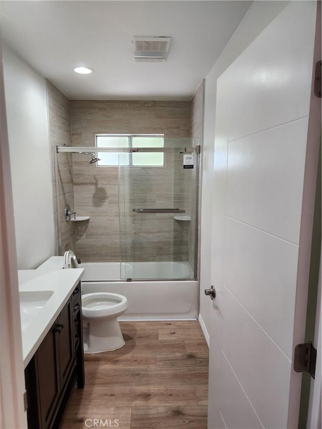 full bathroom with vanity, wood-type flooring, shower / bath combination with glass door, and toilet