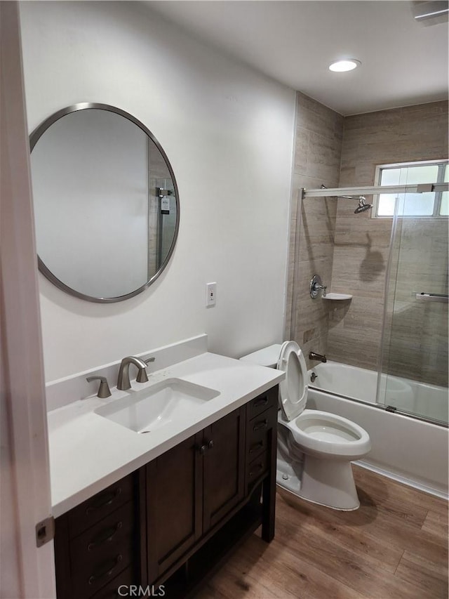 full bathroom with vanity, hardwood / wood-style flooring, toilet, and combined bath / shower with glass door