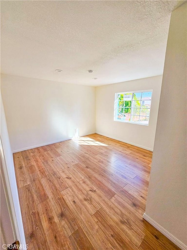 spare room featuring light hardwood / wood-style floors and a textured ceiling