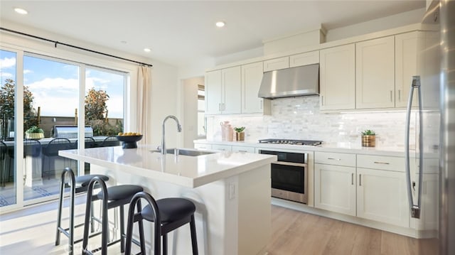 kitchen with white cabinets, appliances with stainless steel finishes, an island with sink, and sink