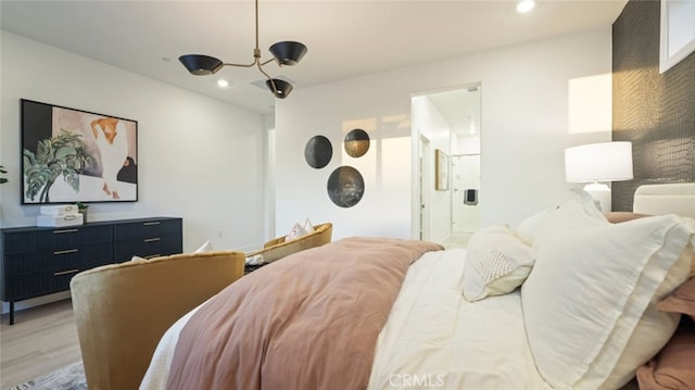 bedroom featuring light hardwood / wood-style floors, connected bathroom, and a notable chandelier