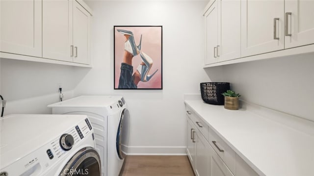 washroom with hardwood / wood-style flooring, cabinets, and washer and clothes dryer