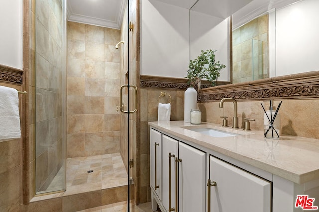 bathroom with ornamental molding, tile walls, a shower with shower door, and vanity