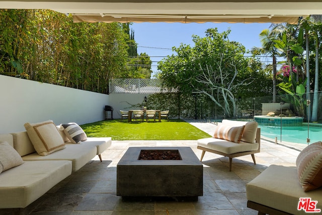 view of patio featuring a fenced in pool and an outdoor living space with a fire pit