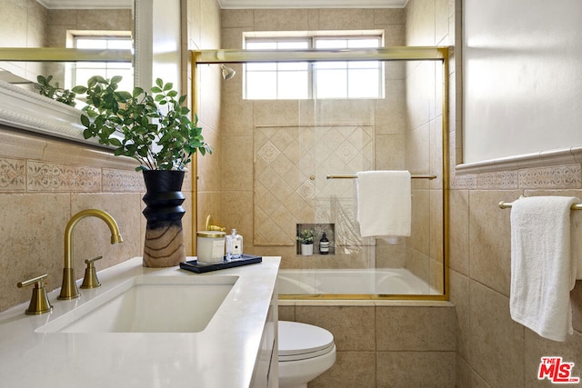 full bathroom featuring toilet, bath / shower combo with glass door, tile walls, and a wealth of natural light