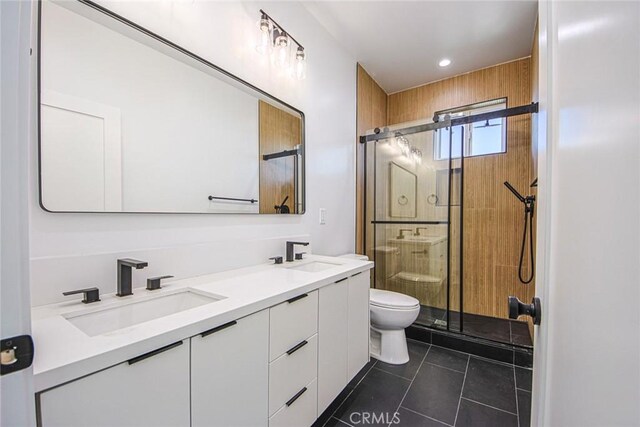 bathroom featuring toilet, vanity, tile patterned flooring, and a shower with shower door