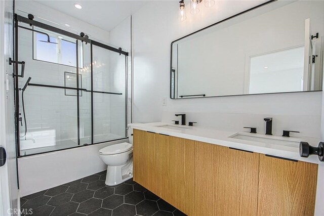 full bathroom featuring toilet, bath / shower combo with glass door, tile patterned floors, and vanity