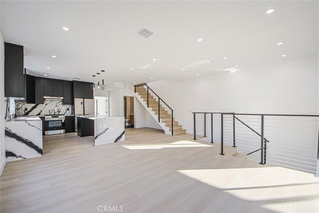 unfurnished living room featuring sink and light hardwood / wood-style flooring