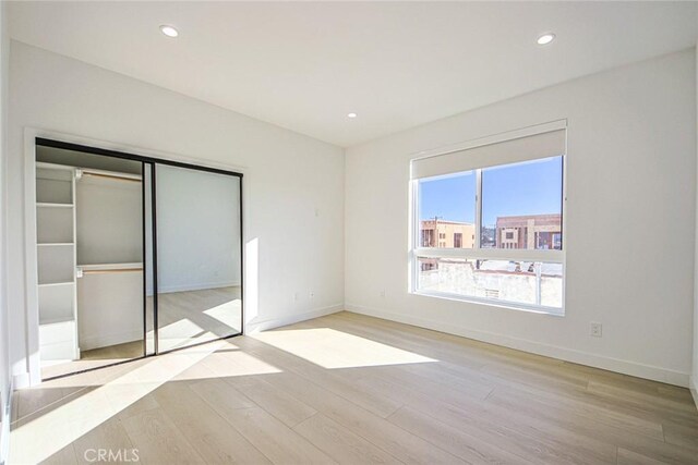 unfurnished bedroom with a closet and light hardwood / wood-style floors