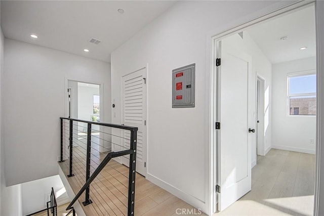 corridor with electric panel and light hardwood / wood-style floors