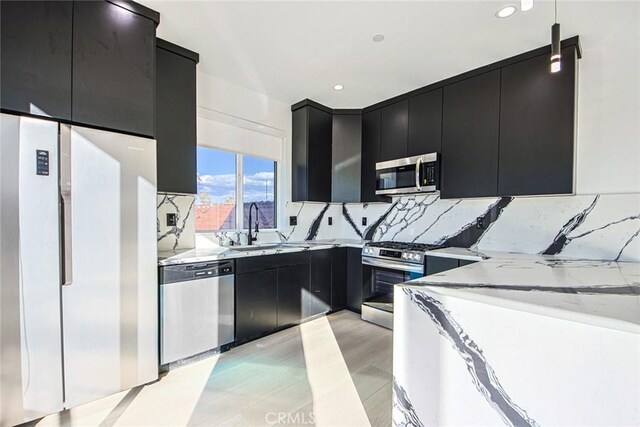 kitchen featuring light stone counters, appliances with stainless steel finishes, tasteful backsplash, and sink