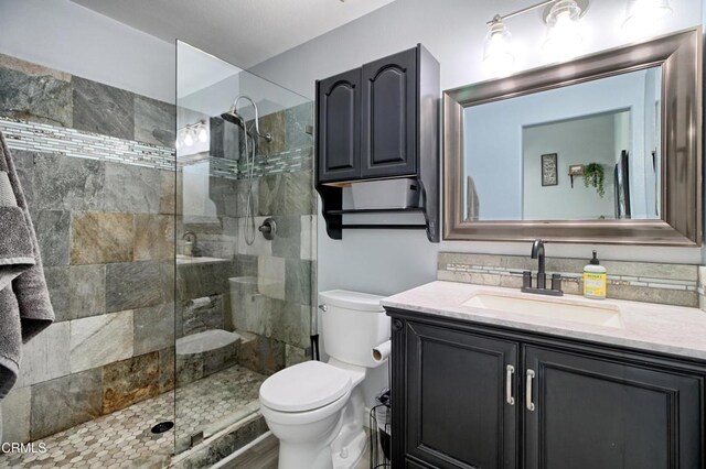 bathroom featuring toilet, vanity, tiled shower, and tasteful backsplash