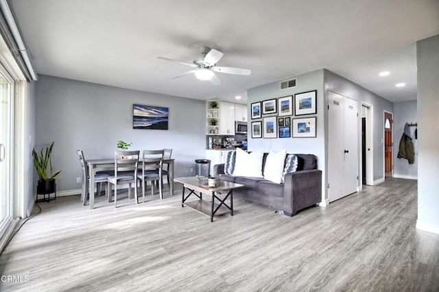 living room with ceiling fan and light wood-type flooring