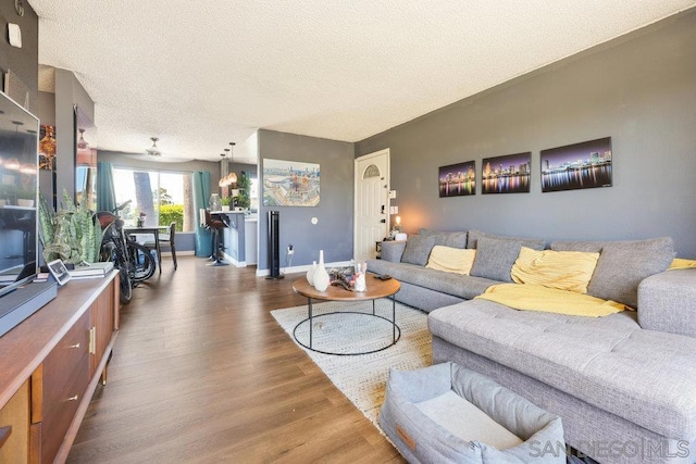 living room featuring a textured ceiling, dark wood-type flooring, and ceiling fan