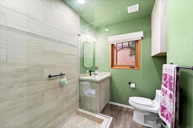 bathroom featuring toilet, vanity, and tiled shower