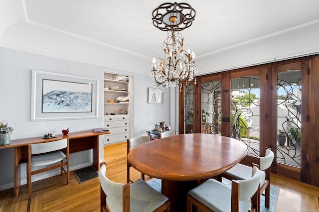 dining space with built in features, a chandelier, and light hardwood / wood-style floors