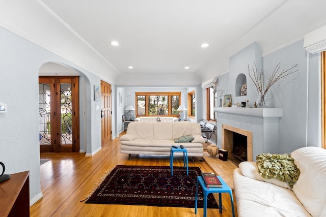 living room featuring light wood-type flooring, french doors, and a tiled fireplace