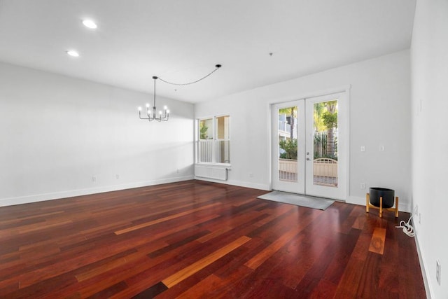 empty room featuring an inviting chandelier, dark hardwood / wood-style flooring, and french doors