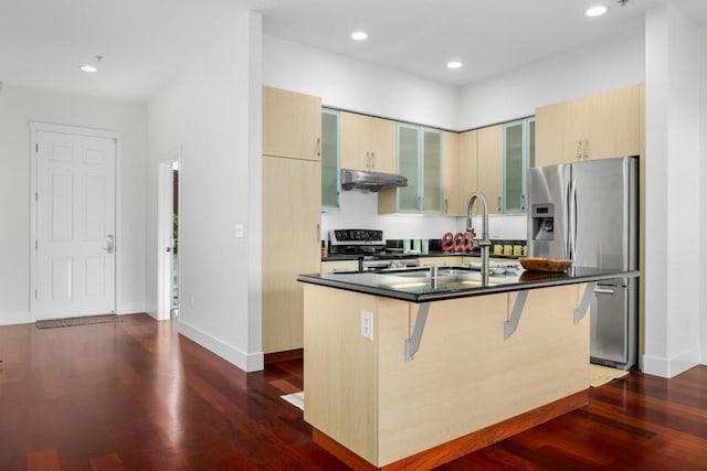 kitchen with sink, a kitchen breakfast bar, stainless steel appliances, dark wood-type flooring, and a center island with sink