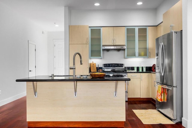 kitchen with dark hardwood / wood-style floors, stainless steel appliances, a kitchen breakfast bar, and a center island with sink