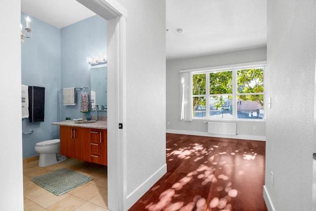 bathroom featuring tile patterned flooring, radiator, vanity, and toilet