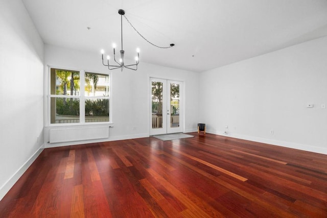 unfurnished dining area featuring hardwood / wood-style flooring, radiator heating unit, a chandelier, and french doors