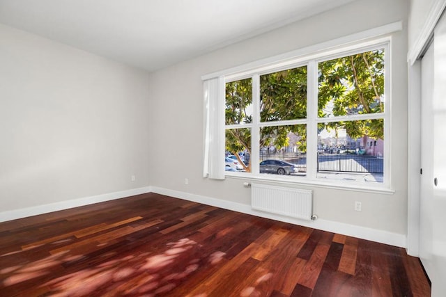 spare room featuring hardwood / wood-style flooring and radiator heating unit