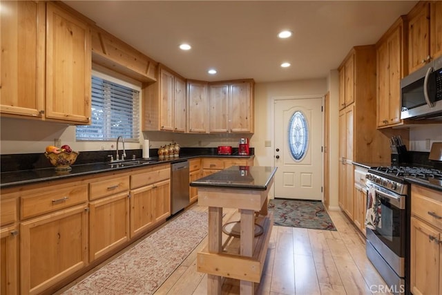 kitchen featuring a kitchen island, light brown cabinets, stainless steel appliances, light hardwood / wood-style floors, and sink